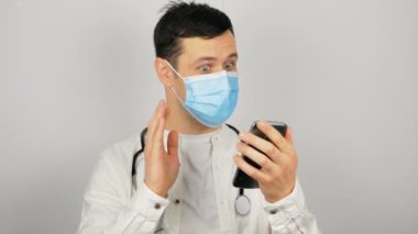 Yakışıklı genç bir doktor hastasıyla görüntülü konuşma ve tedavi yoluyla konuşur. Genç bir doktor karantina sırasında hastaya görüntülü görüşme yoluyla danışmanlık yapar..