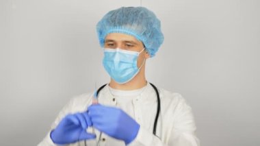 Genç ve yakışıklı bir doktor aşıya hazırlanır, şırıngayı aşıdan önce aşıyla hazırlar. Doktorlar şırıngayı aşıyla doldurur ve enjeksiyona hazırlanır.