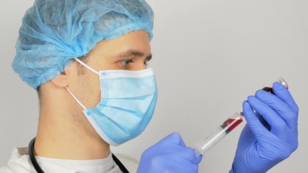 Νεαρός όμορφος γιατρός προετοιμάζεται για τον εμβολιασμό Covid- 19, προετοιμάζει μια σύριγγα με ένα εμβόλιο πριν από την ένεση. Ο γιατρός γεμίζει μια σύριγγα με ένα κόκκινο εμβόλιο, προετοιμάζοντας την ένεση ενός ασθενούς. — Αρχείο Βίντεο