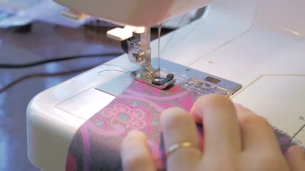 인자 한 주부가 재봉틀을 사용하여 옷을 만들고 있다. 젊고 매력적 인 여성 패션 디자이너의 손을 클로즈업 한 그녀는 재봉틀 위에서 새로운 모델의 드레스를 꿰매고 있습니다. 가까이 서 찍은 사진 — 비디오