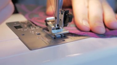 İlgili genç bir ev hanımı dikiş makinesi kullanarak koruyucu maskeler dikiyor. Karantina sırasında genç ve çekici bir kadın gönüllüyü yakından çekerek tıbbi koruyucu maskeler dikiyor. Şunun yakın çekimi: