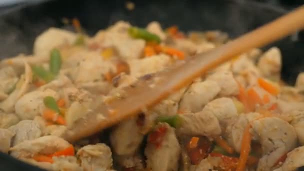 Ο σεφ ανακατεύει κοτόπουλο με λαχανικά σε ένα τηγάνι. Ένας επαγγελματίας σεφ ετοιμάζει κοτόπουλο με λαχανικά σε γουόκ. Το ζουμερό φιλέτο κοτόπουλου τηγανίζεται σε γουόκ με φρέσκα λαχανικά. — Αρχείο Βίντεο