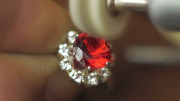 Der Juwelier ist damit beschäftigt, einen Edelstein auf einen Goldring zu schneiden. Ein professioneller Juwelier poliert einen roten Edelstein auf einem Goldring mit einem speziellen Werkzeug. — Stockvideo