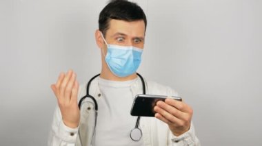 Yakışıklı genç bir doktor, hastasıyla görüntülü konuşma ve tedavi yoluyla konuşuyor..