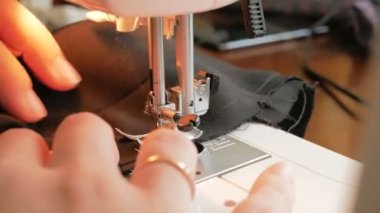 Karantina sırasında genç ve çekici bir kadın gönüllüyü yakından çekerek tıbbi koruyucu maskeler dikiyor. İlgili genç bir ev hanımı dikiş makinesi kullanarak koruyucu maskeler dikiyor. Şunun yakın çekimi: