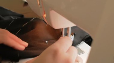 Karantina sırasında genç ve çekici bir kadın gönüllüyü yakından çekerek tıbbi koruyucu maskeler dikiyor. İlgili genç bir ev hanımı dikiş makinesi kullanarak koruyucu maskeler dikiyor. Şunun yakın çekimi: