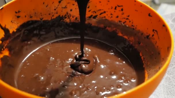 Kocken häller chokladdeg i en bakning maträtt medan du förbereder en födelsedagstårta. Närbild av en kock hälla chokladdeg i en bakning skålen och placera den på en plåt. — Stockvideo