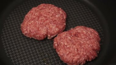 Bir şef ızgaraya köfte koyar. Tavada kızartılmış sulu bir sığır pirzolası. Biftek pirzolası ve ızgarada bir hamburger..