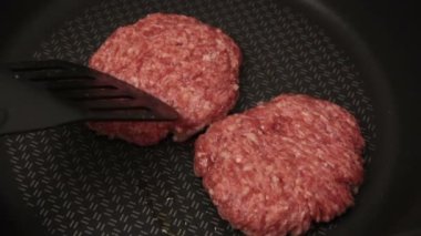 Bir şef ızgaraya köfte koyar. Tavada kızartılmış sulu bir sığır pirzolası. Biftek pirzolası ve ızgarada bir hamburger..