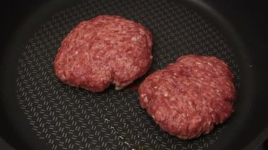 Bir şef ızgaraya köfte koyar. Tavada kızartılmış sulu bir sığır pirzolası. Biftek pirzolası ve ızgarada bir hamburger..