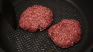 Bir şef ızgaraya köfte koyar. Tavada kızartılmış sulu bir sığır pirzolası. Biftek pirzolası ve ızgarada bir hamburger..