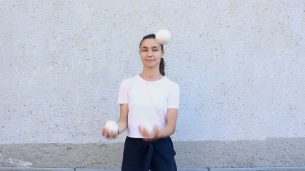 Professionelle Zirkusartisten jonglieren auf der Straße mit weißen Bällen. Ein professioneller Jongleur jongliert mit weißen Bällen. Eine attraktive Jongleurin trainiert ihre Jonglierkünste. — Stockvideo