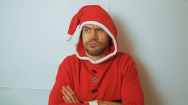 Kırmızı santaclaus karnaval kostümü giymiş genç yakışıklı bir adam mutlu bir şekilde botlarını çırpıyor ve mutlu yıllar ve mutlu Noeller diliyor. Noel Baba kostümü giymiş çekici, komik bir genç.