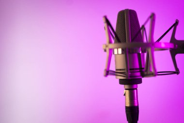 Ses ve müzik stüdyosundaki büyük diyafram mikrofonunu düz arkaplanda seslendirip söylüyor..