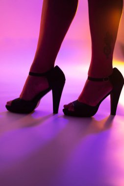 Seksi kıvrımlı bayanın bacakları ve yüksek topuklu topuklu ayakkabıları disko dans ışıklarında gece kulübünde..