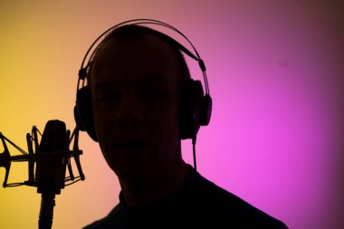 Voiceover artist voice actor in vocal recording studio with larg diaphragm microphone and antipop shield. clipart