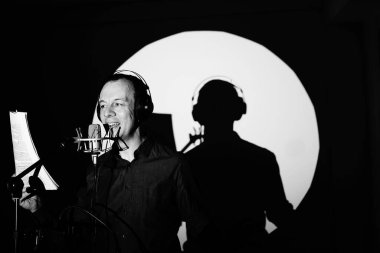 Stüdyo mikrofonunda şarkı söyleyen erkek şarkıcı albüm kapağı tasarımında.