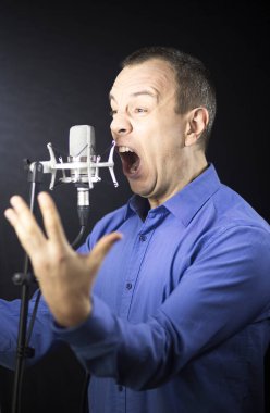 Voiceover artist voice actor in vocal recording studio with larg diaphragm microphone and antipop shield. clipart