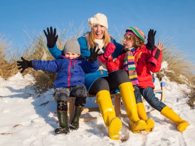 Mother and small children sitting on sledge clipart