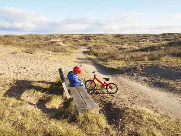 Petit garçon assis à côté de vélo dans les dunes — Photo