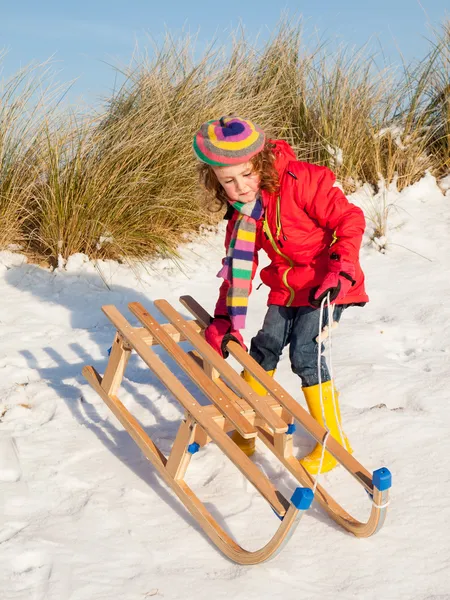 Small girl playing with a wooden sledge — Stock Photo, Image