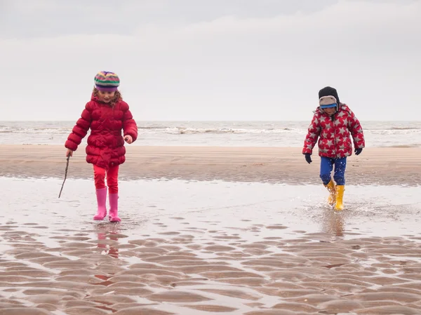 Küçük erkek ve kız sahilde kürek çekmeye — Stok fotoğraf