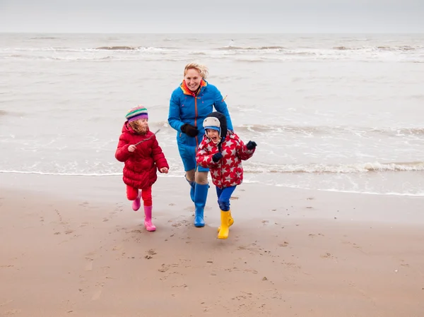 Donna e due bambini piccoli che giocano sulla spiaggia invernale — Foto Stock