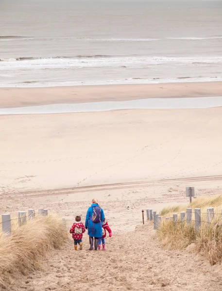 Woman and two small children walking down to the beach — Stock Photo, Image