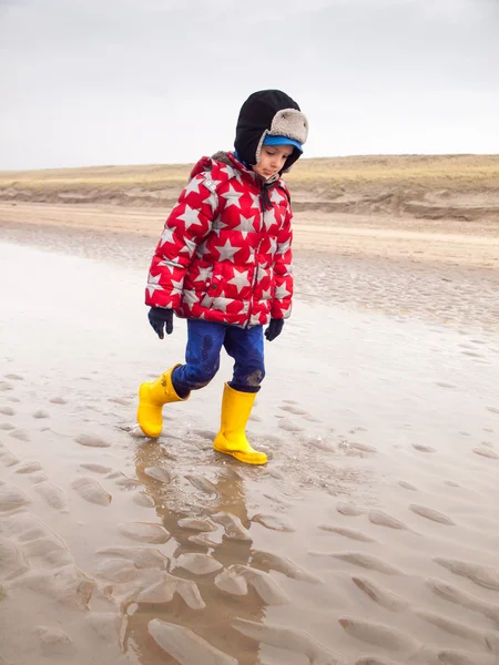 Kleiner Junge spaziert im Winter am Strand Stockbild