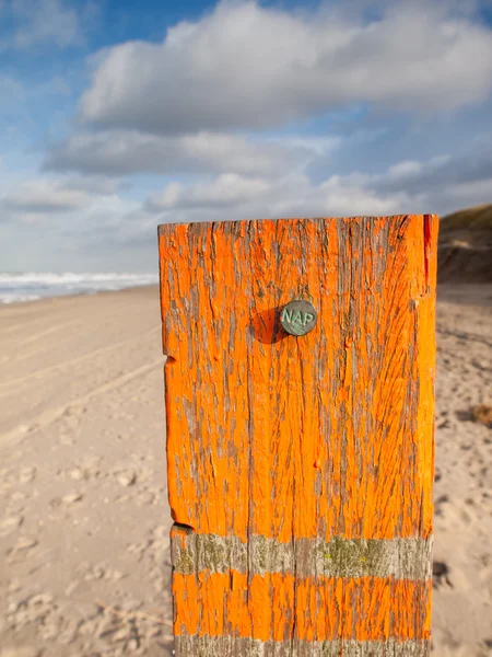 Beach post with sea level marker with beach behind — Stock Photo, Image