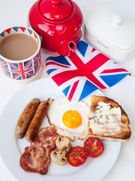Bacon, ovos e salsichas com xícara de chá, bule de chá, torrada e bri — Fotografia de Stock
