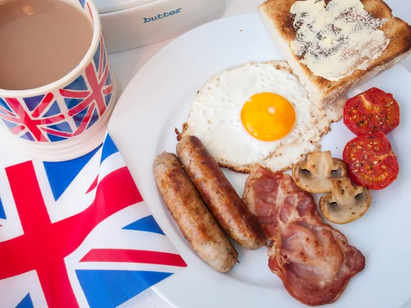 Bacon e uova con tazza di tè, pane tostato e bandiera britannica Foto Stock Royalty Free