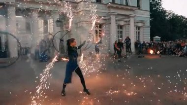 Büyük maytaplarla dönen kız oyuncu gösterisi. Altın kıvılcım kıvılcımlar.