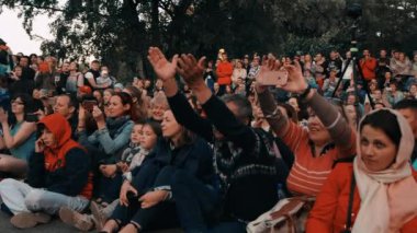 Ateş gösterisi. Seyirciler asfalta oturur, telefonda film izlerler., 