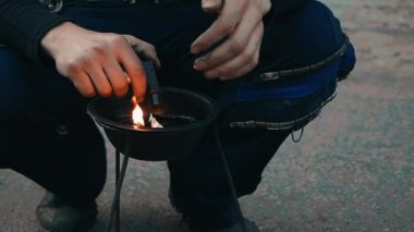 Adam yangın başlamadan önce çömelir ve kasede ateş yakar..