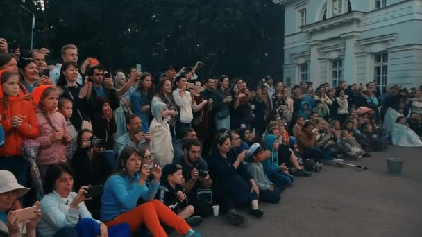 Feuershow. Zuschauer stehen und sitzen auf dem Asphalt, Filmvorführung am Telefon, — Stockvideo