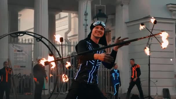 The performer of fire show spins a tripod with burning torches around the edges. — Stock Video