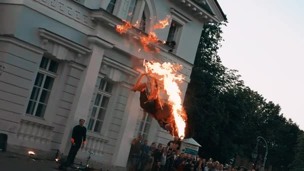 Muž v kombinézách udělá salto přes hlavu s ohnivou pochodní v ruce. — Stock video