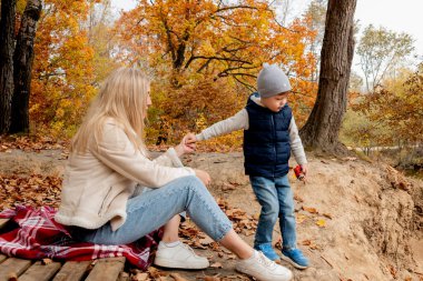 Anne ve oğlu ormanda açık havada oynuyorlar. Aile eğlencesi kavramı. Sonbahar havası.