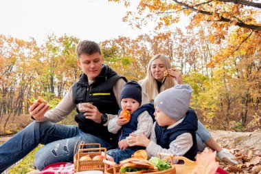 Ailesi göl kenarındaki ormanda dinlenirken piknik yapmış. Aile bireyi bakım konsepti. Sonbahar manzarası. İnsanların çeşitliliği