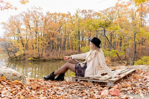 Young Woman Black Hat Sits Shore Lake Autumn Forest Wellness — Stock Photo, Image