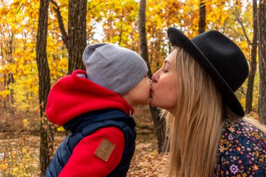 Anne ve oğlu ormanda açık havada oynuyorlar. Aile eğlencesi kavramı. Sonbahar havası.