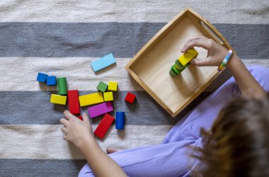 Çocuk renkli ahşap küplerden bir roket yapıyor. Montessori kumaşı. Evde eğitim kavramı. Çevre dostu oyuncak