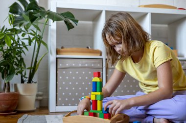 Çocuk renkli ahşap küplerden bir roket yapıyor. Montessori kumaşı. Evde eğitim kavramı. Çevre dostu oyuncak