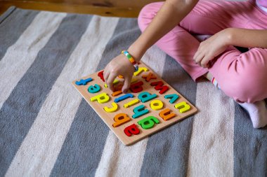 Çocuk kelimeleri harflerden çıkarmayı öğreniyor. İngiliz alfabesi. Montessori kumaşı. Evde eğitim kavramı. Çevre dostu oyuncak