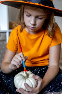 Cadılar bayramı için cadı gibi giyinmiş bir kız balkabağı çizer. Çocuk kaçırma konsepti. Evde eğitim. Montessori malzemesi