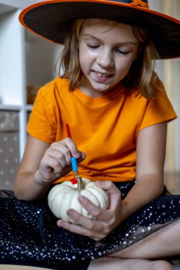 Cadılar bayramı için cadı gibi giyinmiş bir kız balkabağı çizer. Çocuk kaçırma konsepti. Evde eğitim. Montessori malzemesi