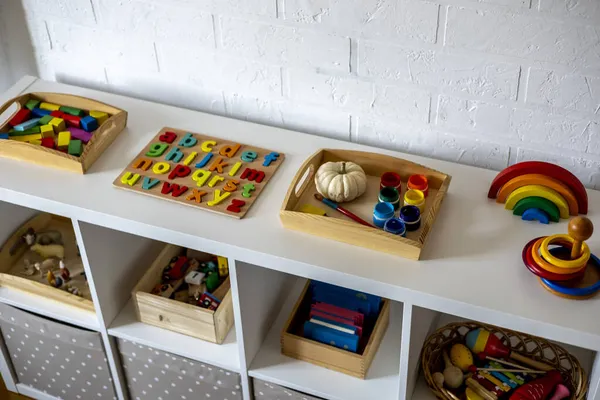 Çocuk odasında sepet ve çekmeceli beyaz raf. Montessori kumaşı. Evde eğitim kavramı. Çevre dostu oyuncak