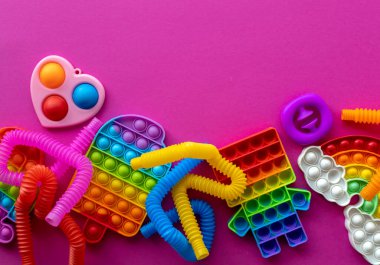 Stres önleyici oyuncaklar eğitim konsepti. Çocuklar arasında popüler bir oyuncak. Pembe arka plan. Patlat ve tüp oyununu patlat. Düz yatıyordu