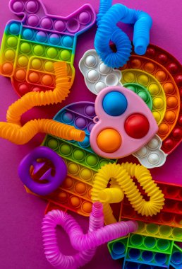 Stres önleyici oyuncaklar eğitim konsepti. Çocuklar arasında popüler bir oyuncak. Pembe arka plan. Patlat ve tüp oyununu patlat. Düz yatıyordu